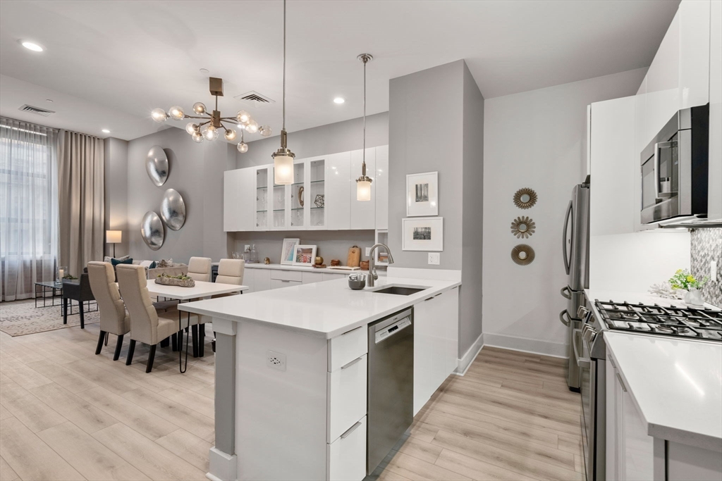 121-127 Portland Street, Unit 202 Boston, MA 02114 - Photo 1 of 25 a large kitchen with cabinets a sink a stove a dining table and chairs