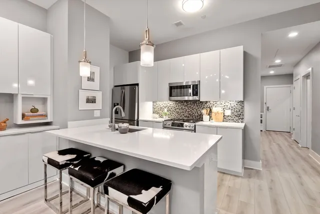 a kitchen with kitchen island a stove a sink a refrigerator and chairs