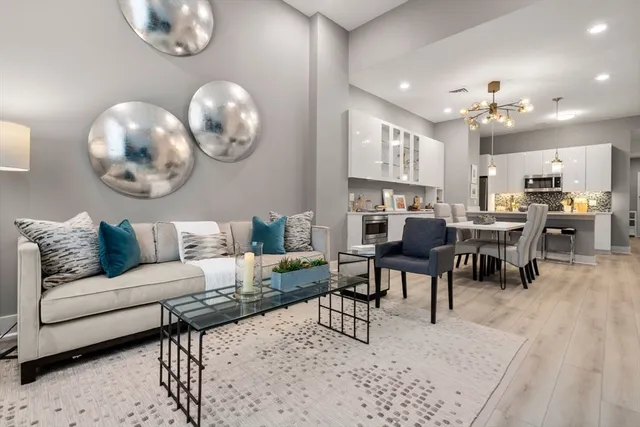 a living room with furniture kitchen view and a chandelier