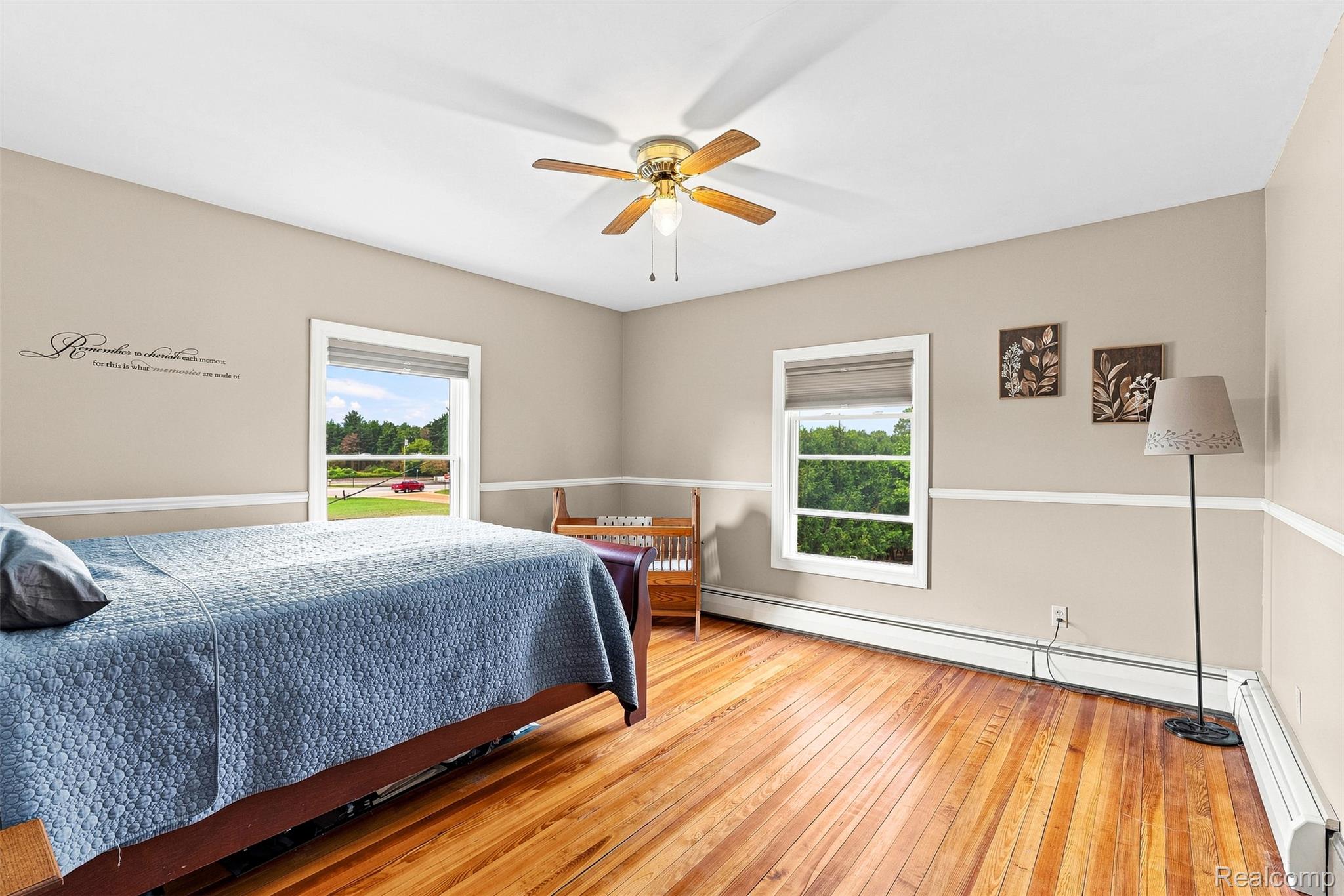 2971 Huron Line Road Cass City, MI 48726 - Photo 29 of 63 Hardwood flooring, two windows with white trim, a ceiling fan with integrated lighting, and neutral wall tones