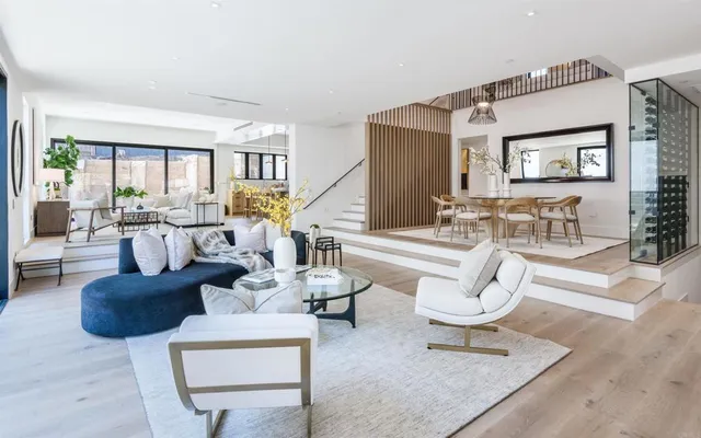 a living room with couches coffee table and a dining table with wooden floor
