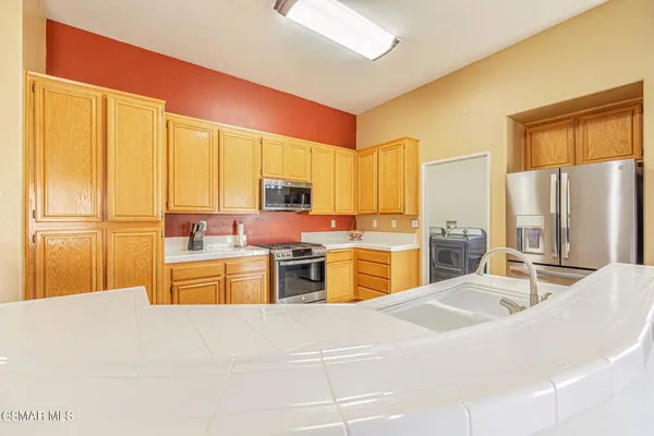 a view of a kitchen with stainless steel appliances granite countertop a refrigerator and a stove top oven