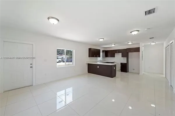 a large white kitchen with a sink a microwave and a refrigerator