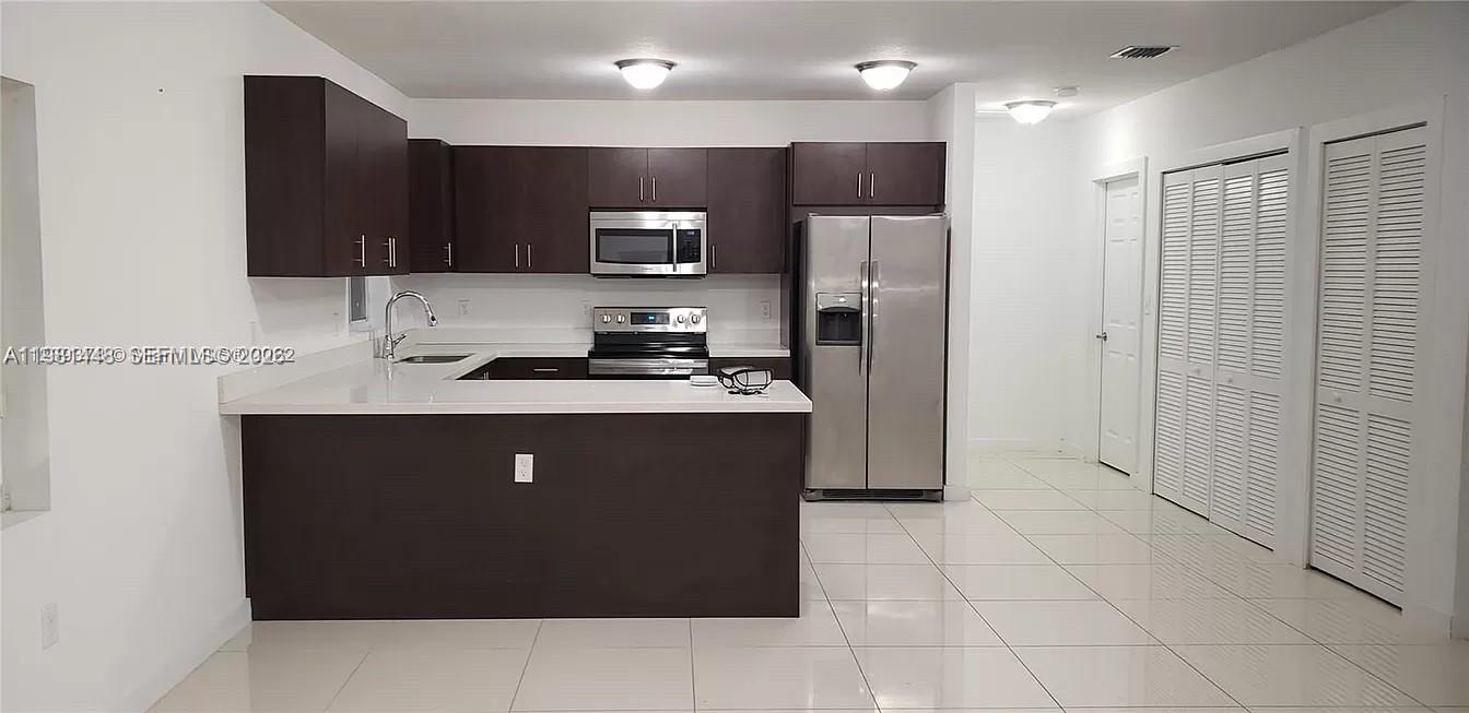 2285 Northwest 91st Street Miami, FL 33147 - Photo 4 of 9 a kitchen with stainless steel appliances a refrigerator stove microwave and sink