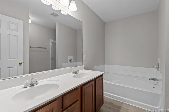 a bathroom with a tub a sink and mirror