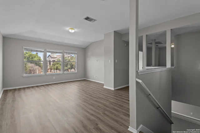 an empty room with wooden floor and windows
