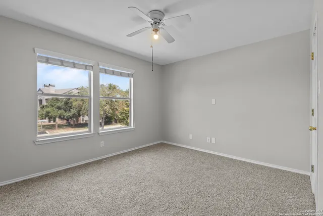 an empty room with a window and a ceiling fan
