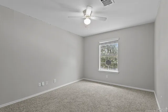 an empty room with a window and a fan