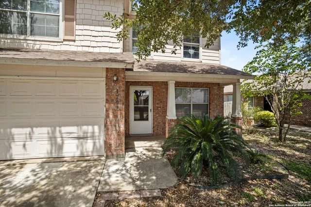 a view of a house with a small yard and a large tree