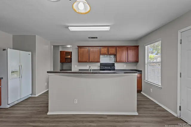 a living room with stainless steel appliances kitchen island a stove a refrigerator and cabinets