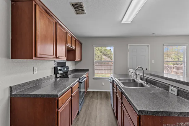 a kitchen with a sink a stove a microwave and wooden cabinets
