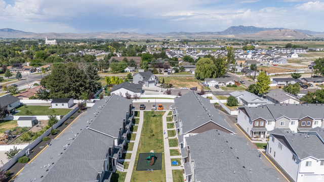 46 West 460 Smithfield, UT 84335 - Photo 30 of 31 Aerial perspective showcasing a community of townhomes with gray shingle roofs and private patios, featuring a central green space with a playground