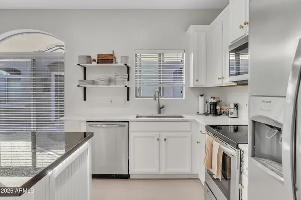 a kitchen with stainless steel appliances granite countertop white cabinets a stove a sink and dishwasher