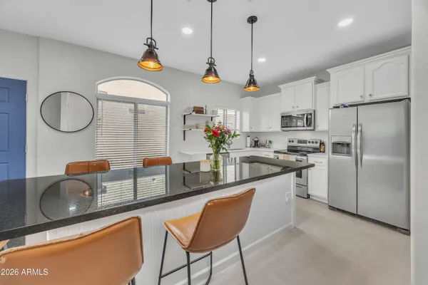 a kitchen with stainless steel appliances granite countertop a sink a stove a refrigerator cabinets and chairs