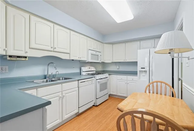 a kitchen with stainless steel appliances granite countertop a refrigerator and white cabinets