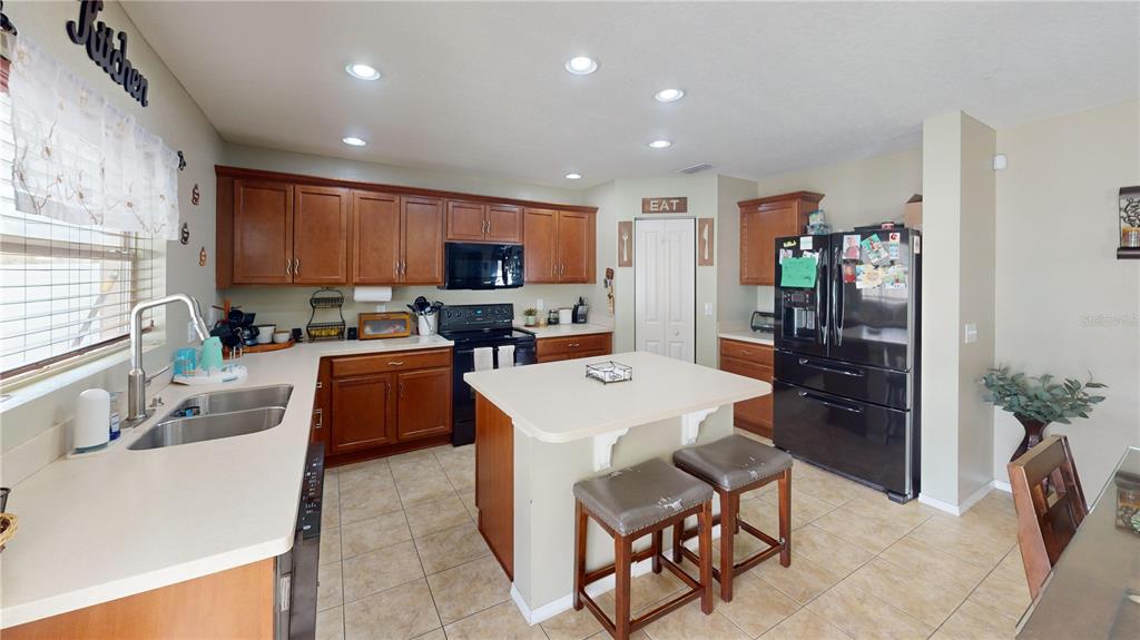 4354 Fieldview Circle Wesley Chapel, FL 33545 - Photo 4 of 15 a kitchen with stainless steel appliances kitchen island granite countertop a refrigerator a stove a sink a stove a dining table and chairs with wooden floor