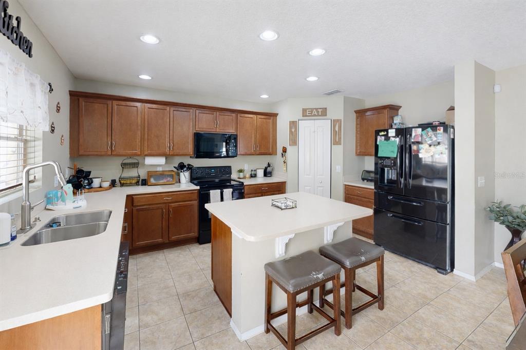 4354 Fieldview Circle Wesley Chapel, FL 33545 - Photo 6 of 15 a kitchen with a refrigerator a stove a sink a dining table and chairs
