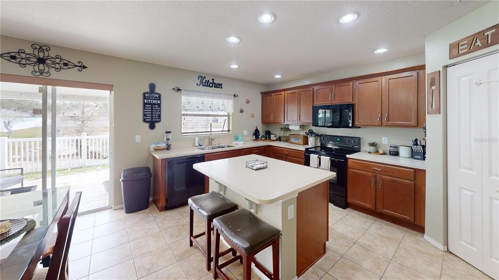 4354 Fieldview Circle Wesley Chapel, FL 33545 - Photo 7 of 15 a kitchen with a refrigerator a stove top oven a sink a dining table and chairs