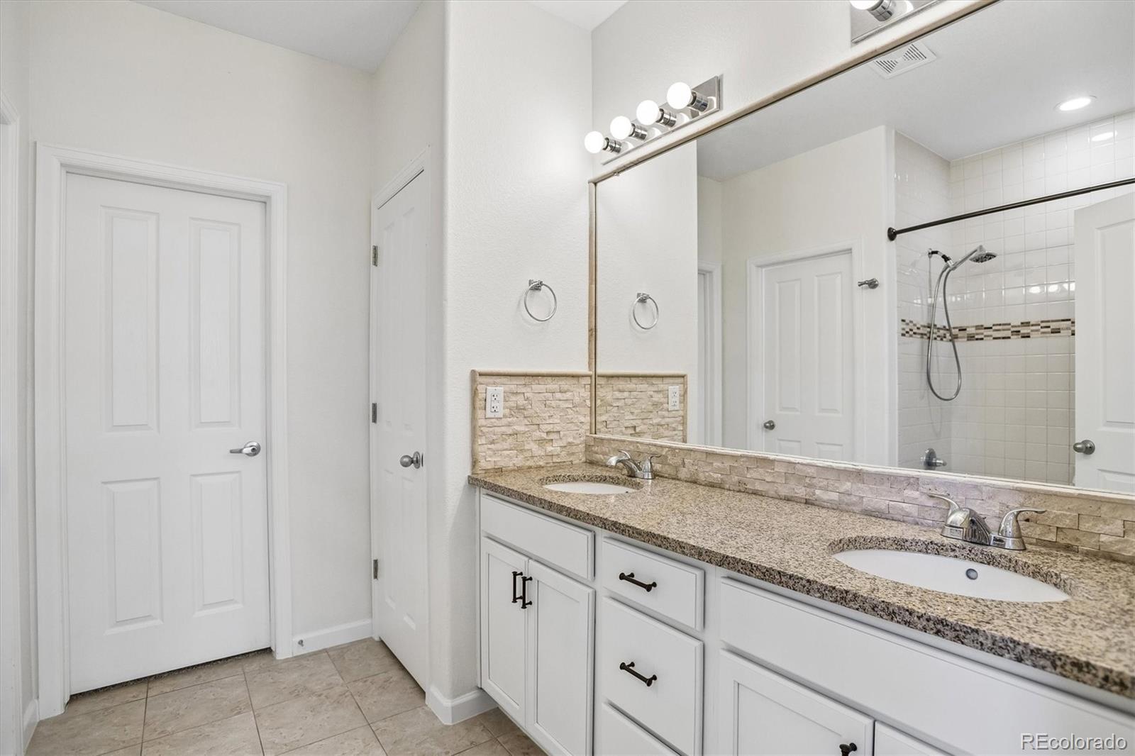 960 Fire Rock Place Colorado Springs, CO 80921 - Photo 14 of 32 a bathroom with a granite countertop double vanity sink mirror and