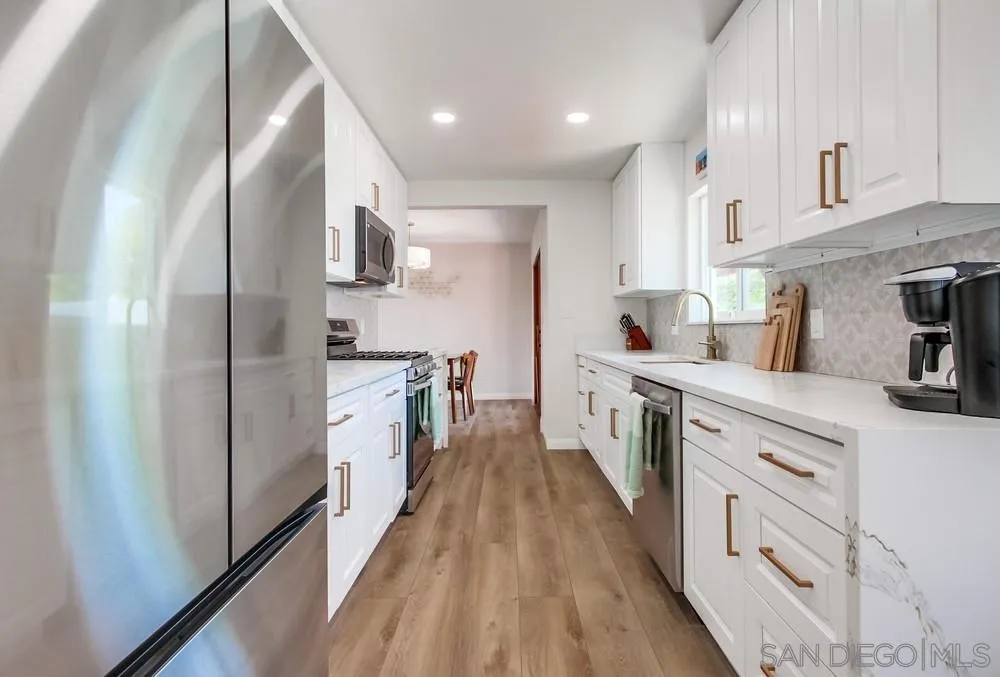 4724 Troy Lane La Mesa, CA 91942 - Photo 16 of 49 a kitchen with stainless steel appliances a stove top oven a sink a refrigerator white cabinets and wooden floor