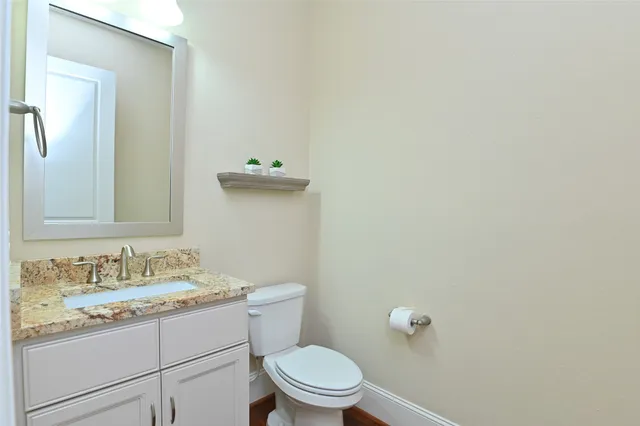 a bathroom with a granite countertop toilet and a sink