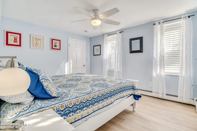 a bedroom with a bed and dresser with wooden floor