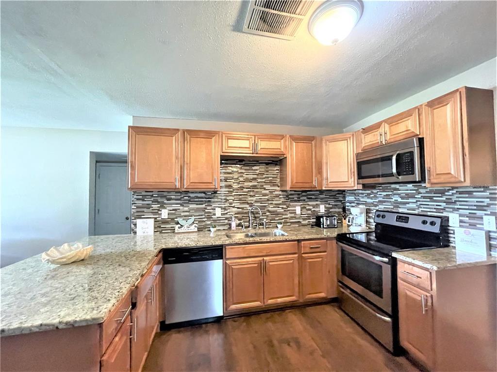 5106 104th Street North St. Petersburg, FL 33708 - Photo 2 of 35 a kitchen with stainless steel appliances granite countertop wooden cabinets and a stove