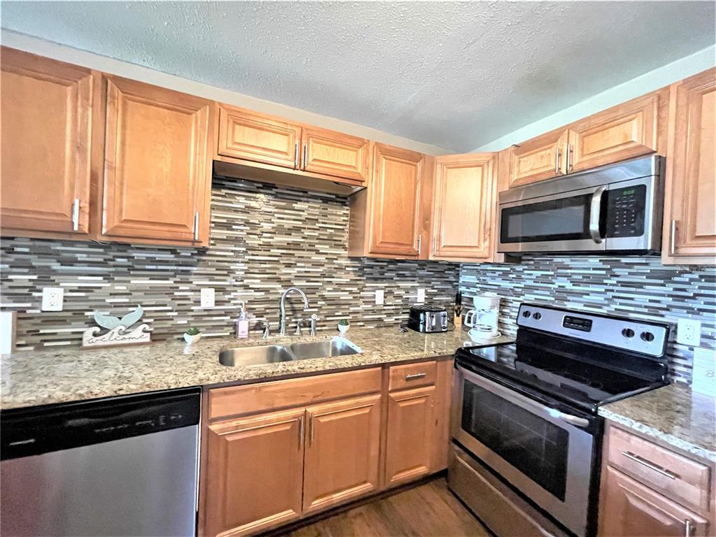 5106 104th Street North St. Petersburg, FL 33708 - Photo 4 of 35 a kitchen with stainless steel appliances granite countertop a sink stove and microwave