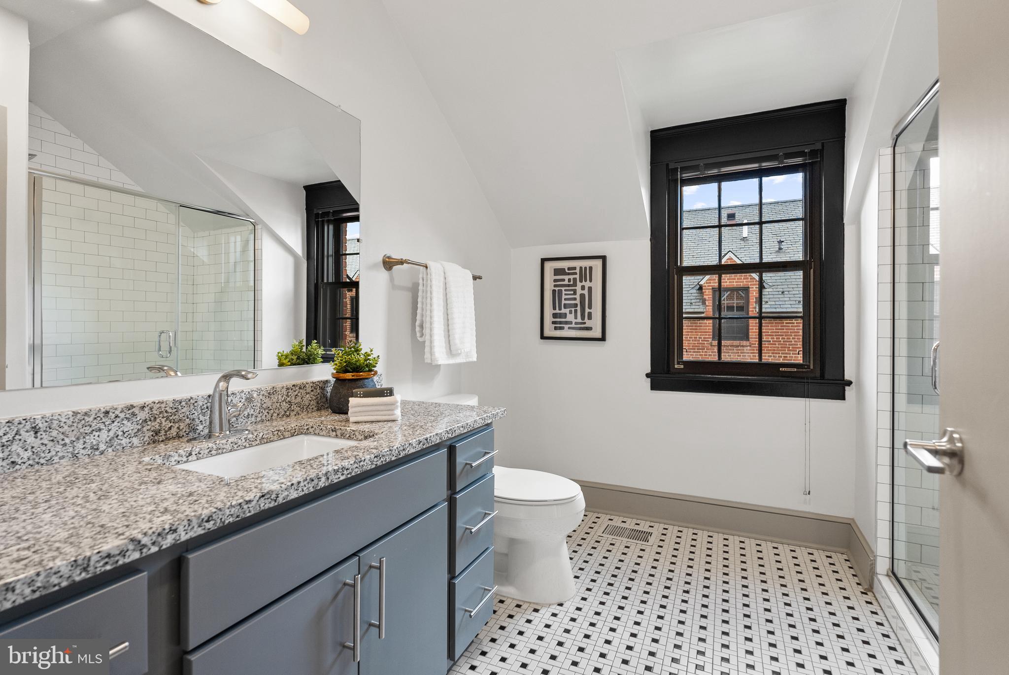 9071 Power House Road, Unit 102 Lorton, VA 22079 - Photo 36 of 50 a bathroom with a granite countertop sink a toilet a mirror and shower