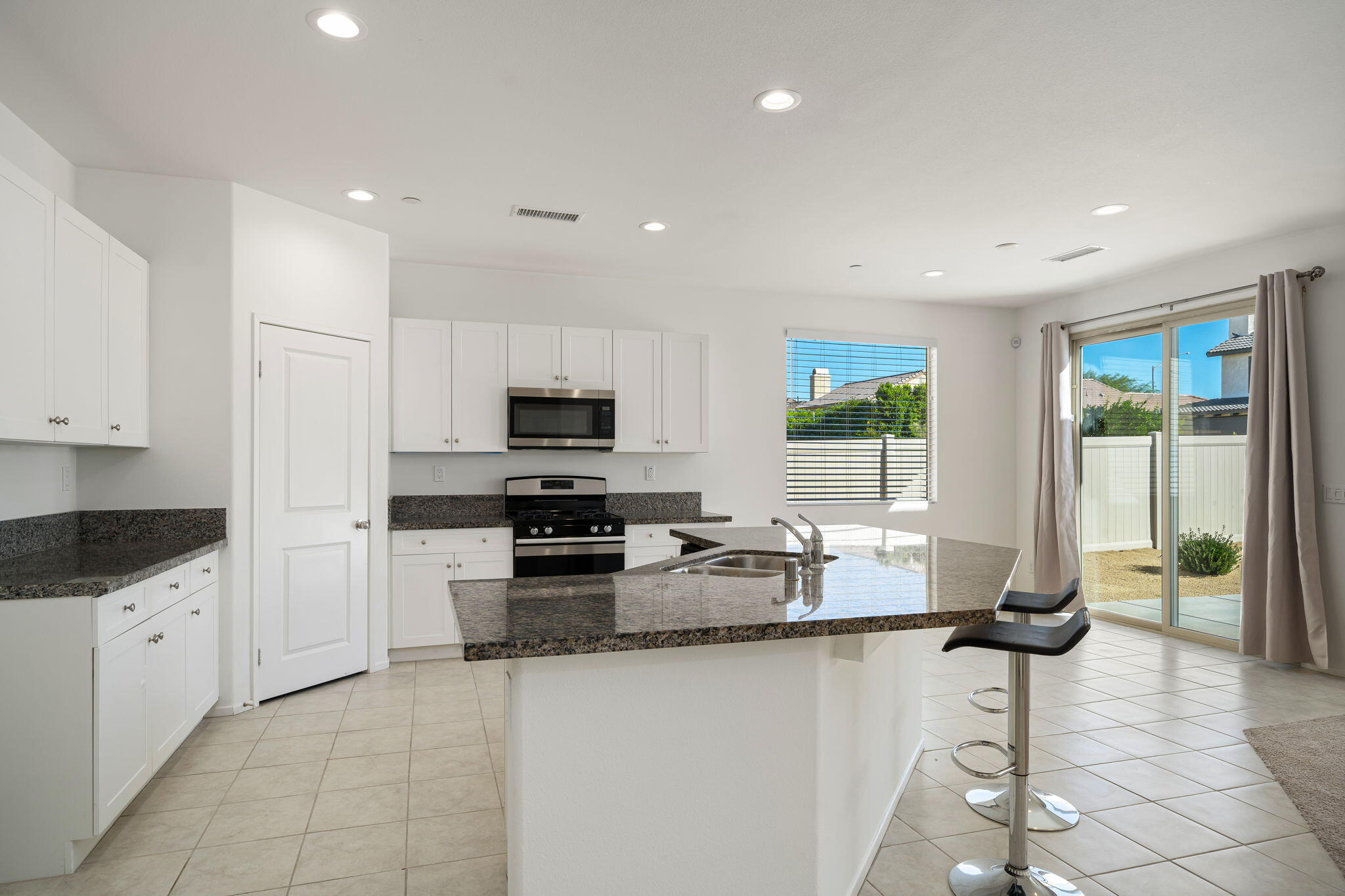 50252 Paseo Barcelona Coachella, CA 92236 - Photo 3 of 23 a kitchen with granite countertop a stove a sink a counter space and cabinets