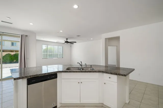 a kitchen with granite countertop a sink and white cabinets