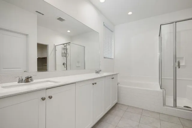 a bathroom with a bathtub shower sink vanity and mirror