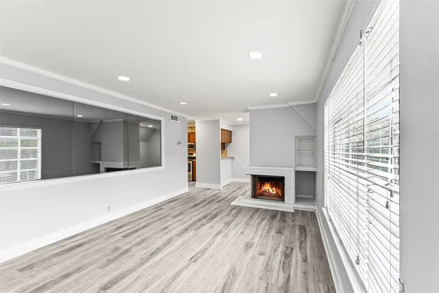 an empty room with wooden floor fireplace and windows