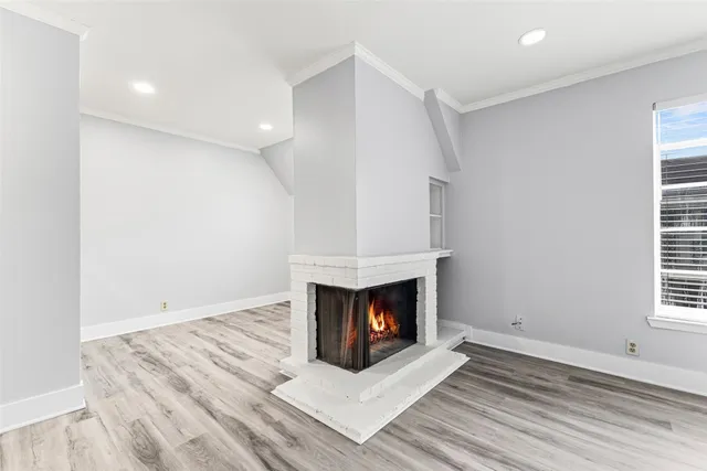 an empty room with wooden floor fireplace and windows