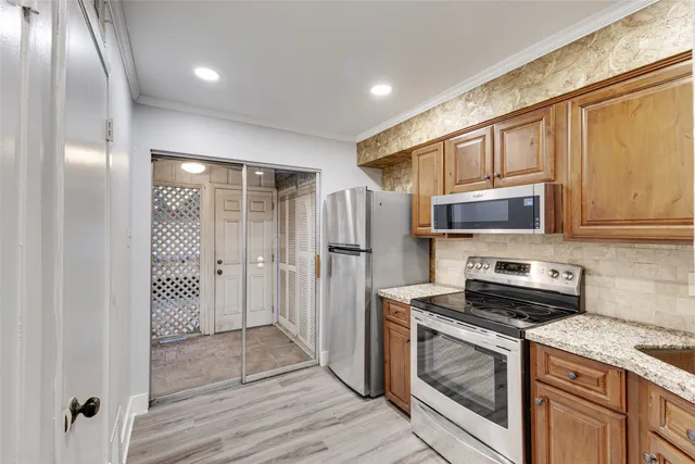 a kitchen with stainless steel appliances granite countertop a refrigerator a stove and a sink with wooden floor