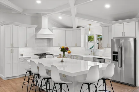 a kitchen with stainless steel appliances a table chairs refrigerator and cabinets