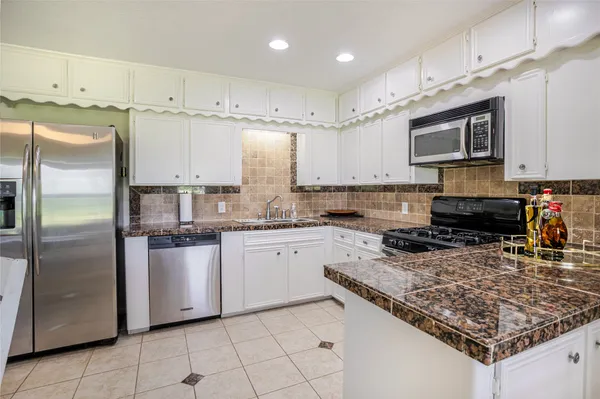 a kitchen with stainless steel appliances granite countertop a sink refrigerator and microwave