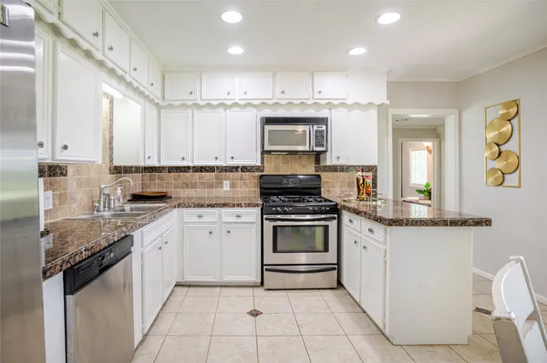 a kitchen with granite countertop a sink stove and cabinets
