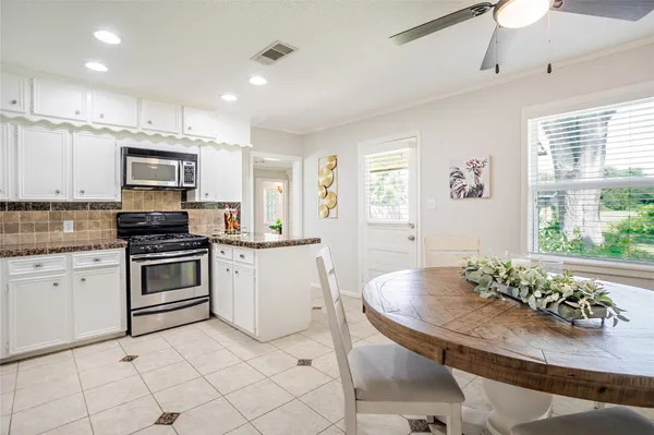 a kitchen with stainless steel appliances granite countertop a stove a sink a microwave a dining table and chairs