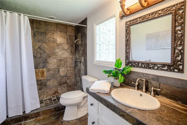 a bathroom with a granite countertop sink toilet a mirror and shower