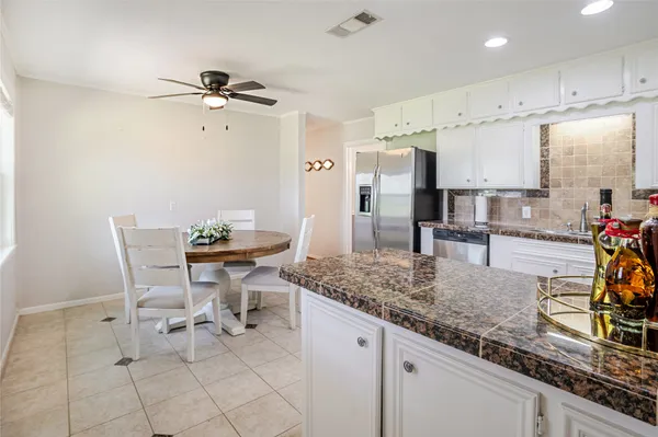 a kitchen with stainless steel appliances granite countertop a sink a stove a dining table and chairs