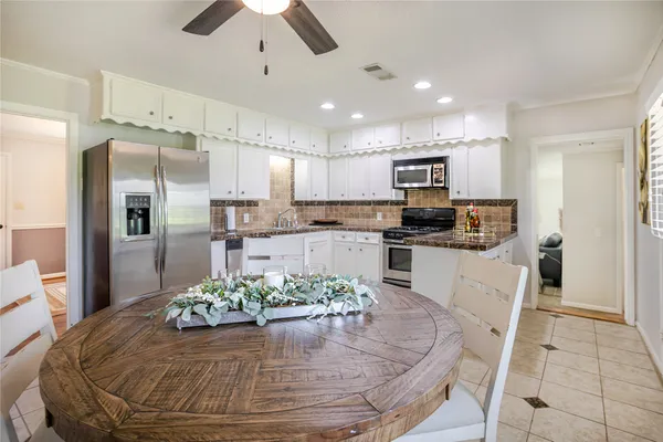 a kitchen with stainless steel appliances granite countertop a stove a refrigerator a oven a sink with a dining table and chairs