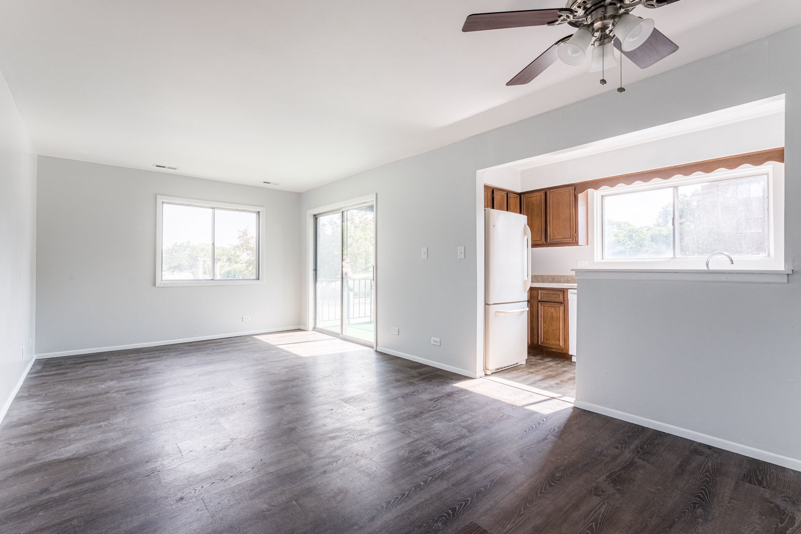 625 West Huntington Commons Road, Unit 106 Mount Prospect, IL 60056 - Photo 2 of 17 a view of a big room with wooden floor a ceiling fan and windows