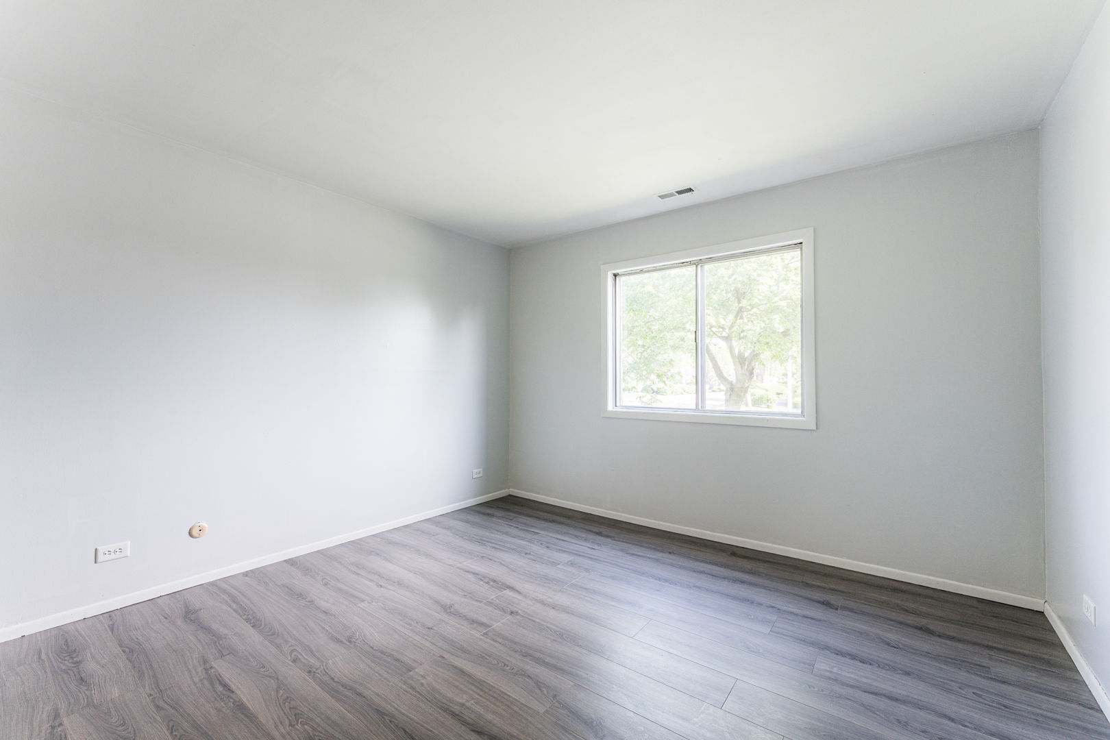 625 West Huntington Commons Road, Unit 106 Mount Prospect, IL 60056 - Photo 7 of 17 an empty room with wooden floor and windows
