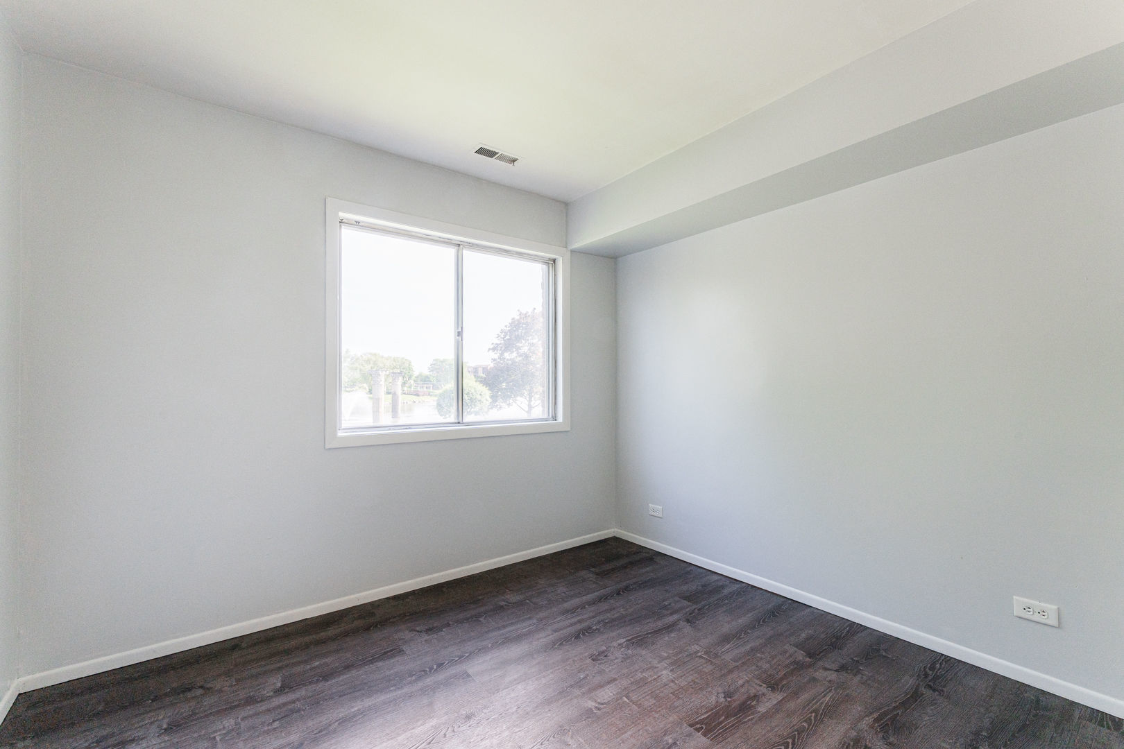 625 West Huntington Commons Road, Unit 106 Mount Prospect, IL 60056 - Photo 8 of 17 an empty room with wooden floor and windows