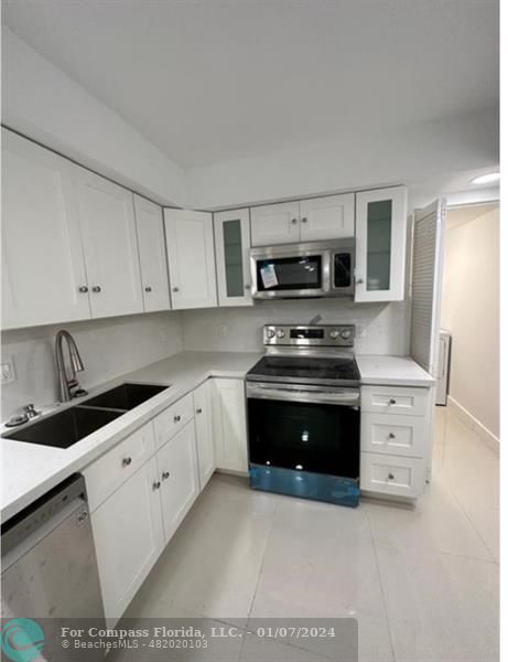 a kitchen with granite countertop a stove a sink and a white cabinets