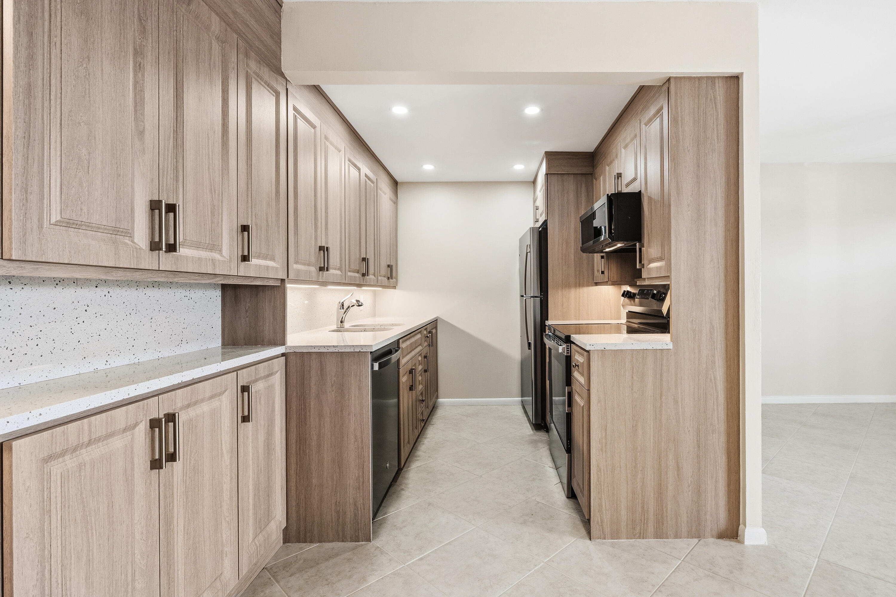 4067 Yarmouth C Boca Raton, FL 33434 - Photo 5 of 39 a kitchen with kitchen island white cabinets and stainless steel appliances