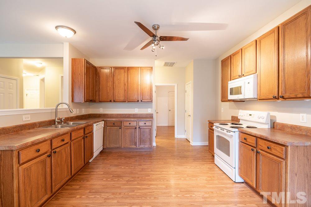 3513 Rendition Street Raleigh, NC 27610 - Photo 8 of 30 a large kitchen with stainless steel appliances granite countertop a sink dishwasher stove and refrigerator with wooden cabinets