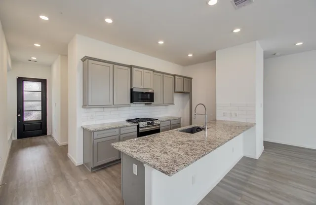 a kitchen with stainless steel appliances granite countertop a sink stove and refrigerator