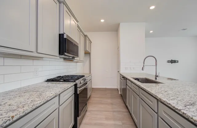 a kitchen with granite countertop sink stainless steel appliances and a counter space